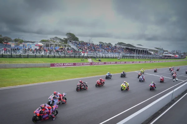 MotoGP riders racing on Phillip Island circuit with the coastline in the background.